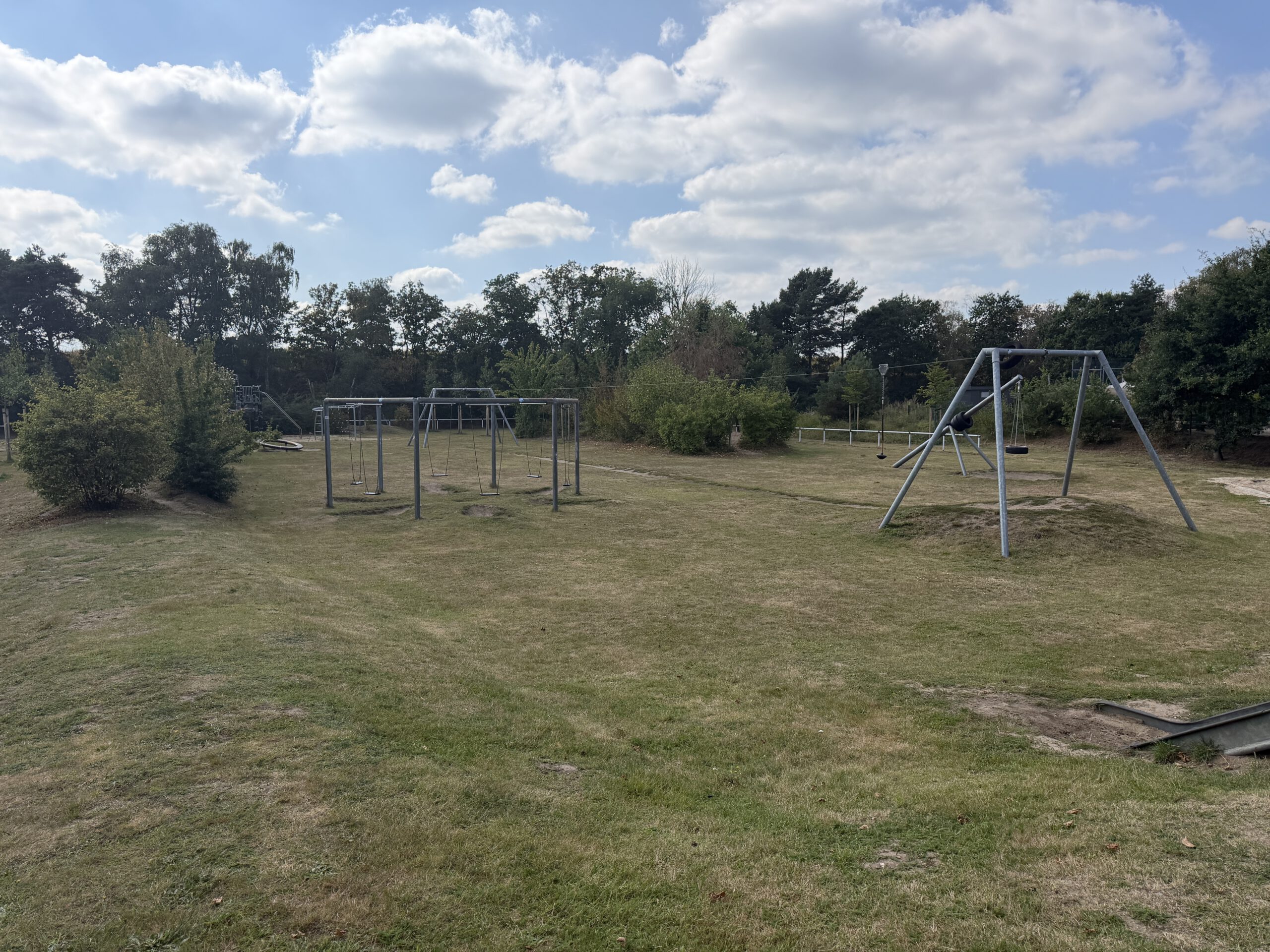Weitläufiges Außengelände der Grundschule Ashausen mit Schaukeln und weiteren Spiel- und Bewegungsflächen.