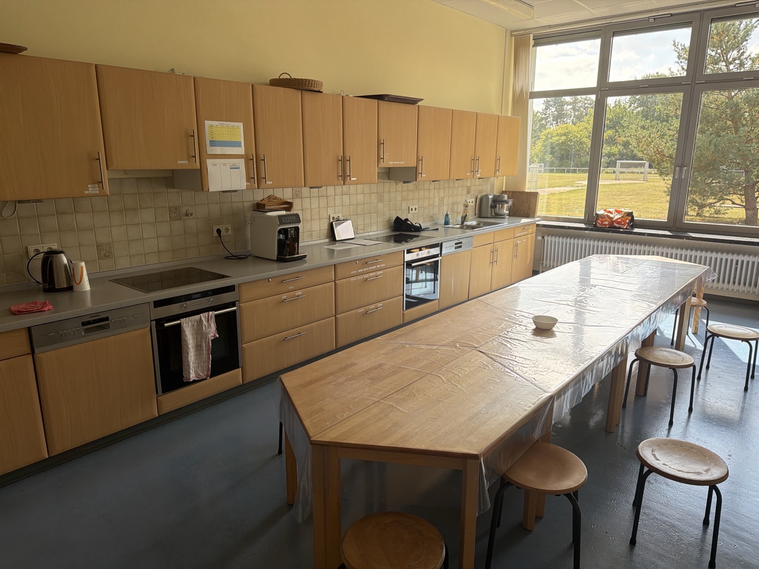 Schulküche der Grundschule Ashausen mit Arbeitsfläche, Küchengeräten und großem Tisch für gemeinsames Kochen und Backen.